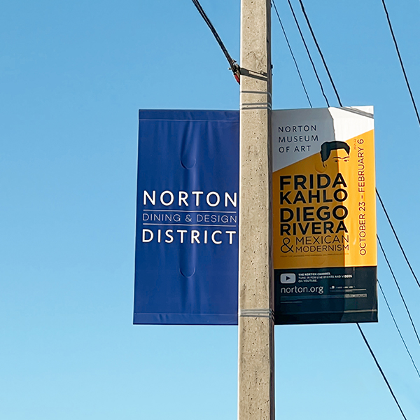 Pole banner for the Dixie Business Association in West Palm Beach, Florida. Featuring a stacked logo reading "Norton Dining & Design District" in white on a blue background using a minimal san serif typeface.