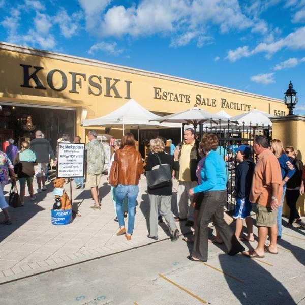 A large line of people outdoors, in front of the yellow "Kofski Antiques" building during one of their sales in West Palm Beach.