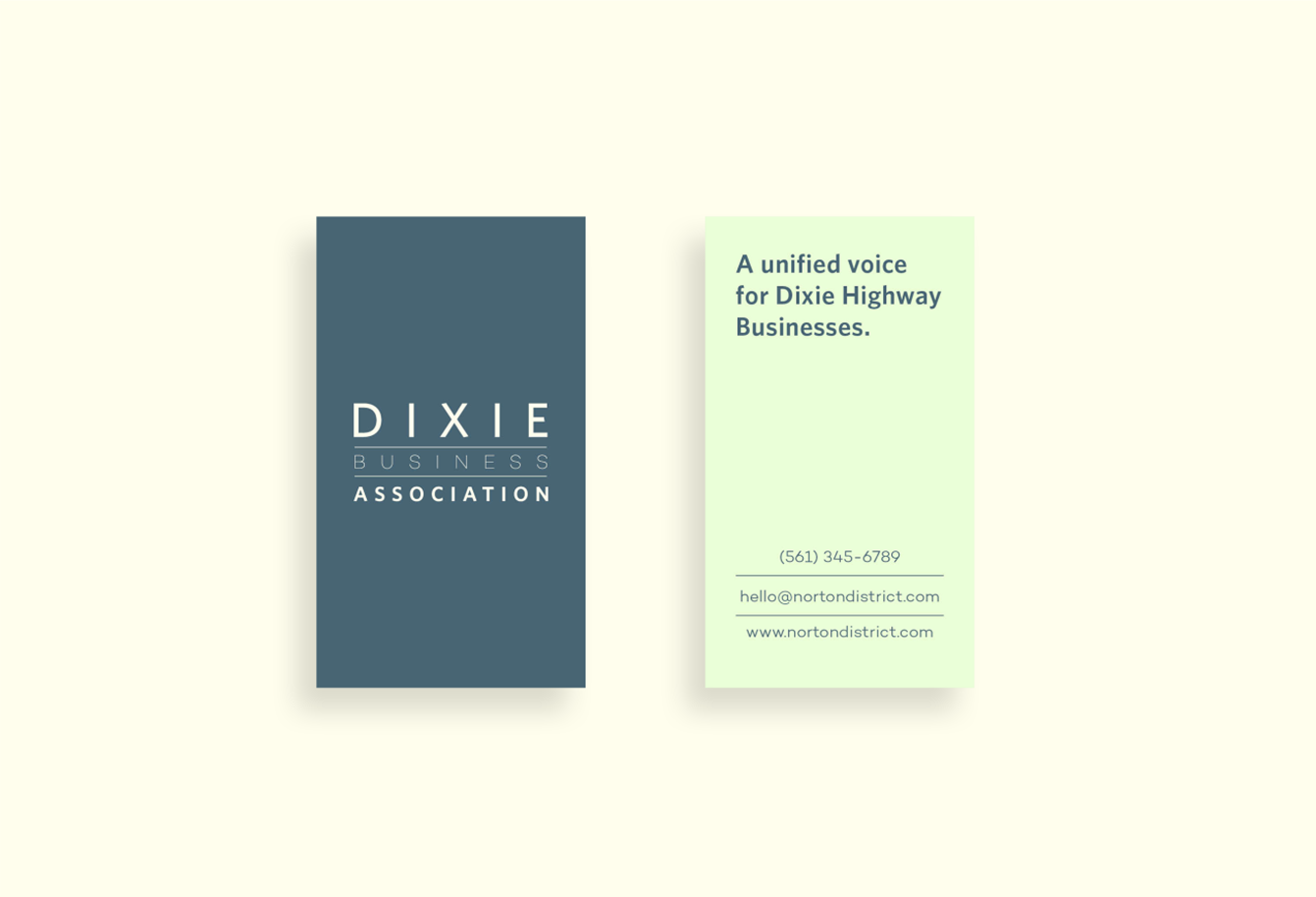 Business card mockups with the Dixie Business Association logo on the front in cream on a blue background, and the back features their tagline 