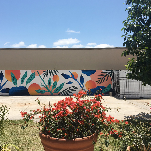 Courtyard at Elizabeth Ave Station in West Palm, showing off the colorful abstract botanical mural done by Melissa Deckert, and black & white grid shipping container painted by Gather & Seek.