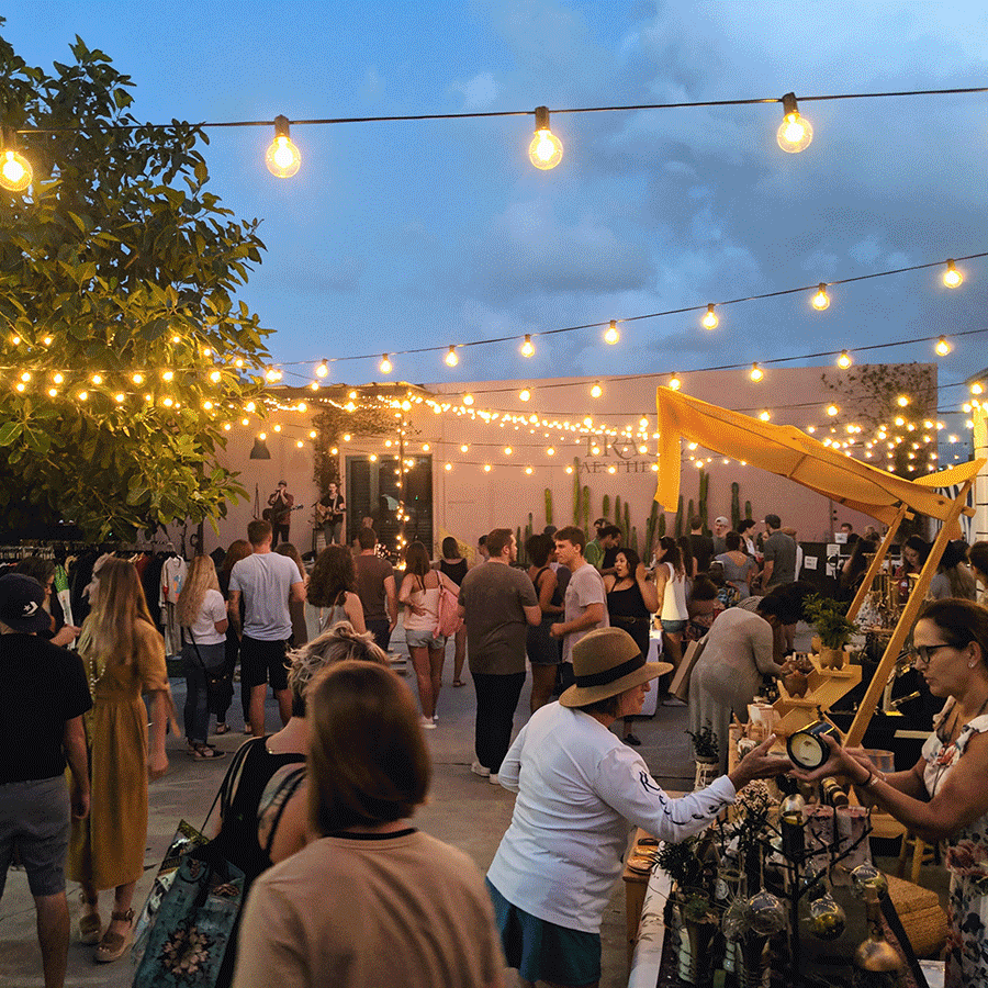 Crowd of party-goers are relaxing under the lights and night sky at Elizabeth Ave Station's pop-up event in West Palm Beach, FL.